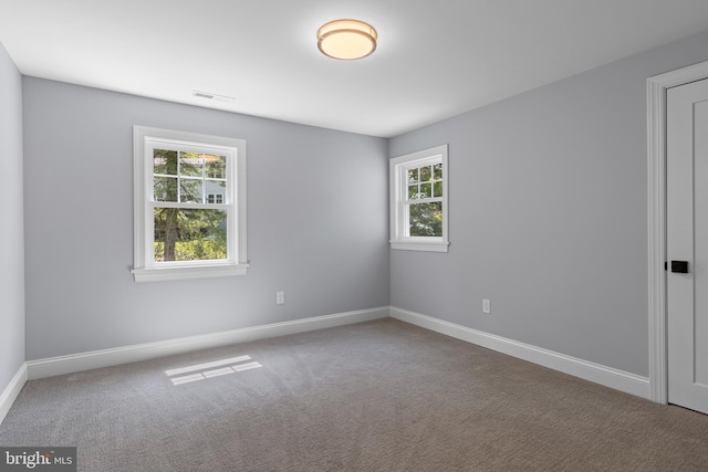 carpeted spare room with baseboards, a healthy amount of sunlight, and visible vents