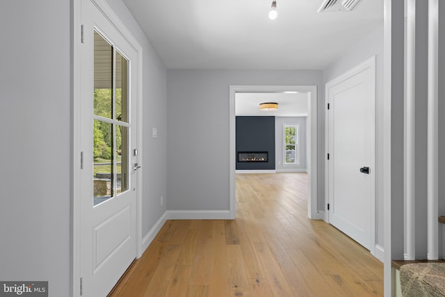 hallway featuring light wood finished floors, visible vents, and baseboards