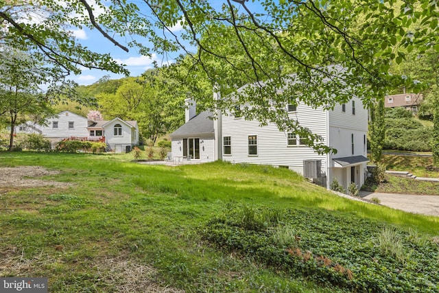 back of house featuring a chimney and a lawn