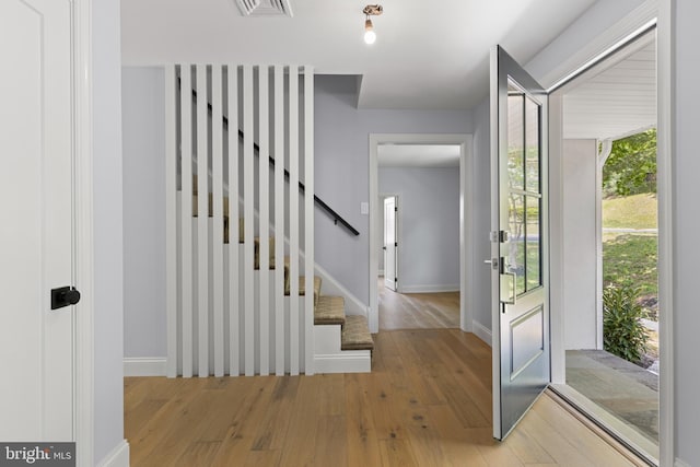 foyer entrance featuring baseboards, stairs, visible vents, and wood-type flooring