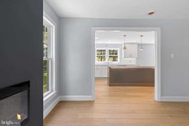 interior space featuring baseboards, a wealth of natural light, light wood finished floors, and a sink