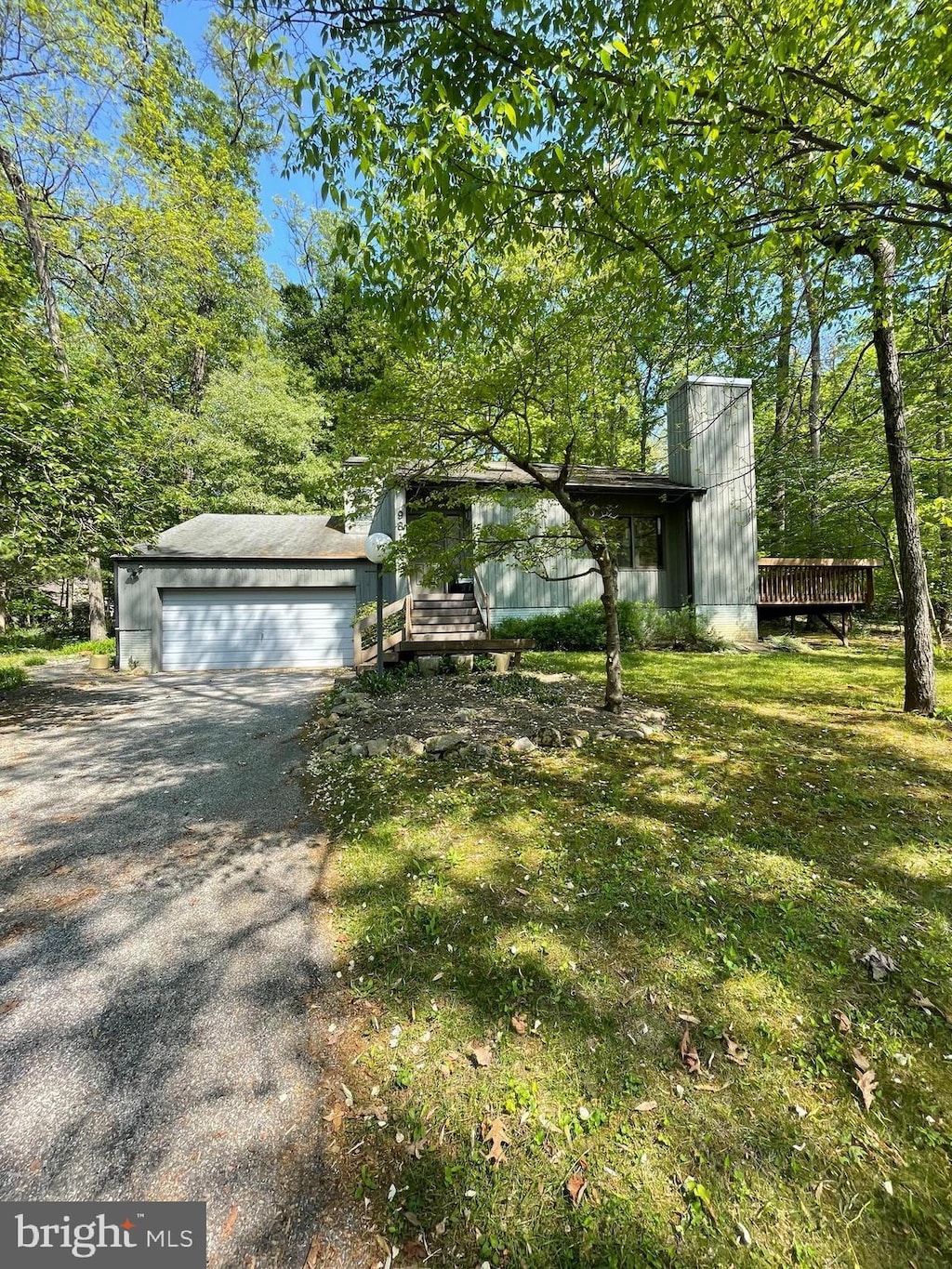 exterior space featuring an attached garage, driveway, and a chimney