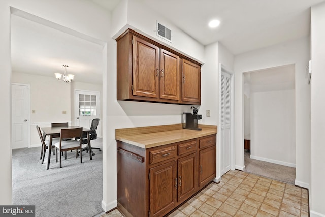 309 Camden Dr, Fredericksburg, VA 22405 - kitchen with brown cabinetry, a chandelier, baseboards, light countertops, and light colored carpet