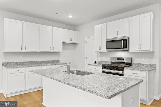 kitchen with a sink, white cabinetry, light wood finished floors, and stainless steel appliances