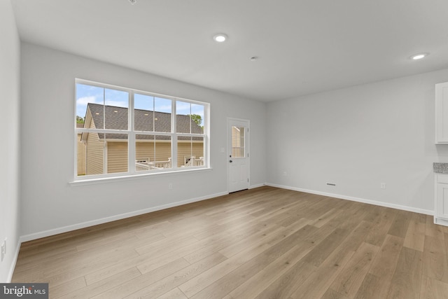 unfurnished living room with recessed lighting, baseboards, and light wood-type flooring