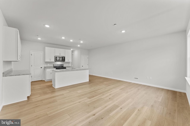 kitchen with recessed lighting, white cabinets, a sink, light wood-style flooring, and stainless steel appliances