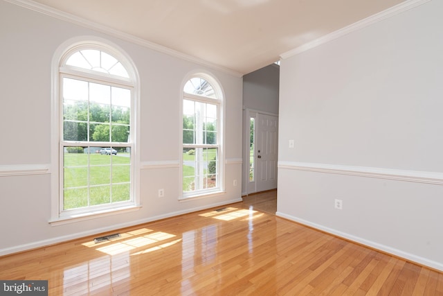 empty room with ornamental molding, wood-type flooring, and baseboards