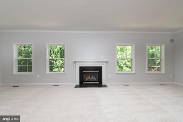 unfurnished living room featuring carpet flooring, ornamental molding, baseboards, a fireplace with flush hearth, and plenty of natural light