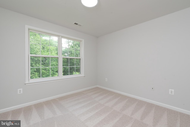 empty room featuring baseboards, light colored carpet, and plenty of natural light
