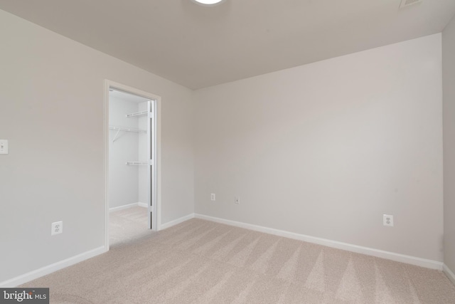 unfurnished bedroom with light carpet, baseboards, a spacious closet, and a closet
