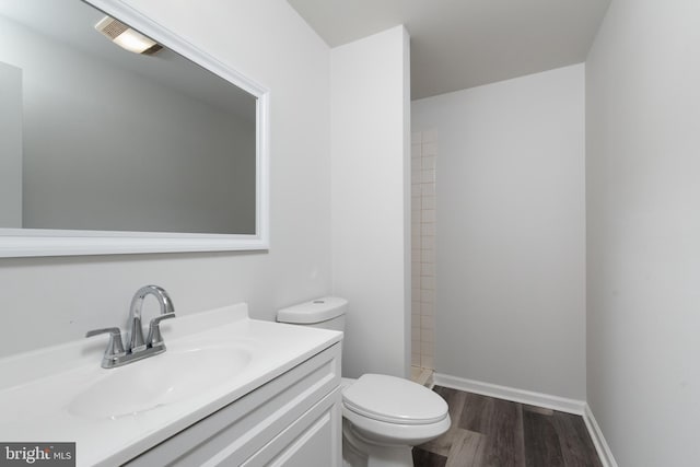 bathroom with toilet, wood finished floors, vanity, and a shower