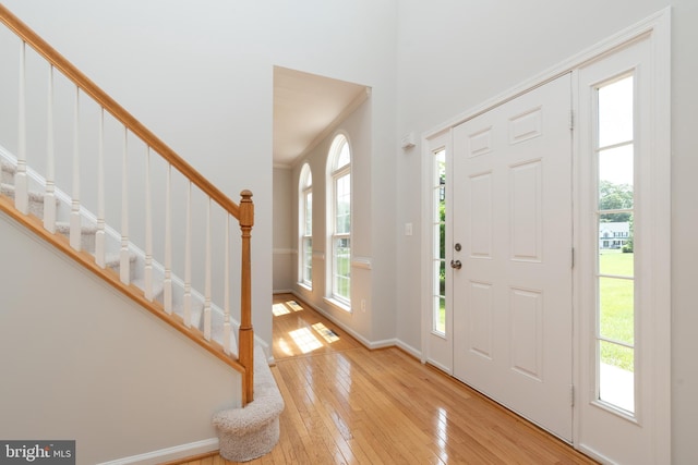 entrance foyer with plenty of natural light, hardwood / wood-style floors, stairs, crown molding, and baseboards
