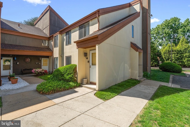 5025A S Convent Ln Unit 142, Philadelphia, PA 19114 - view of front of property with stucco siding, roof with shingles, and a front lawn