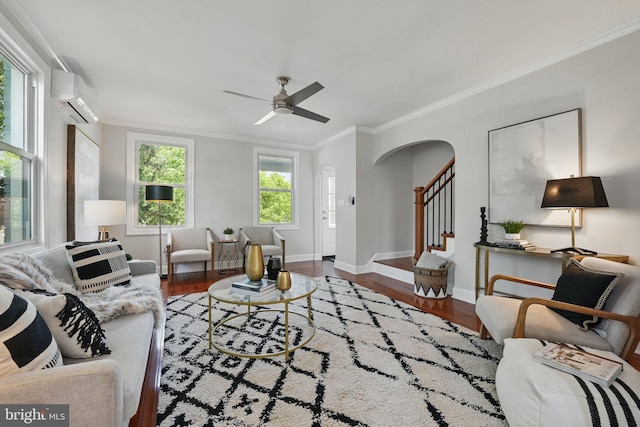 living area featuring ceiling fan, arched walkways, a wall mounted air conditioner, wood finished floors, and ornamental molding