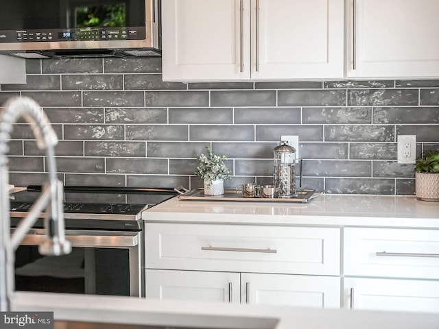 kitchen featuring white cabinetry, stainless steel microwave, and backsplash
