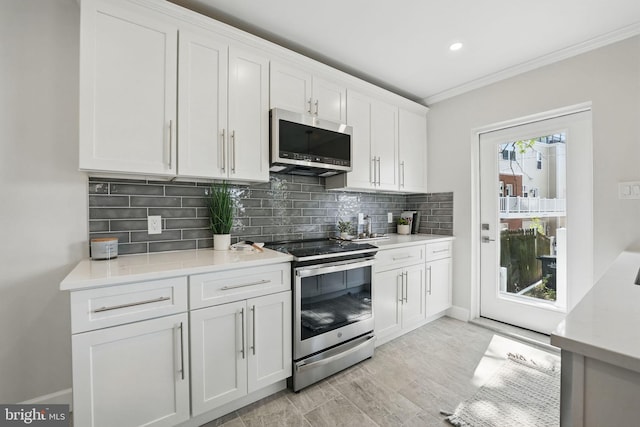 kitchen with appliances with stainless steel finishes, light countertops, white cabinetry, tasteful backsplash, and ornamental molding
