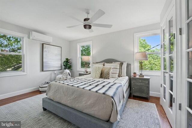 bedroom with baseboards, multiple windows, a wall unit AC, and dark wood-style floors