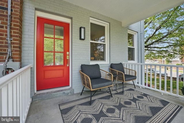 view of exterior entry featuring brick siding and covered porch