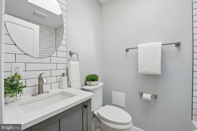 bathroom with vanity, toilet, and tasteful backsplash