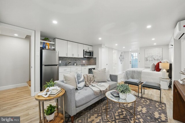 living room with recessed lighting, baseboards, a wall unit AC, and light wood finished floors