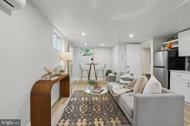 living room featuring recessed lighting, baseboards, a wall mounted air conditioner, and light wood-style floors