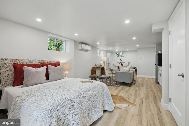 bedroom featuring light wood-style floors, a wall mounted AC, freestanding refrigerator, and recessed lighting