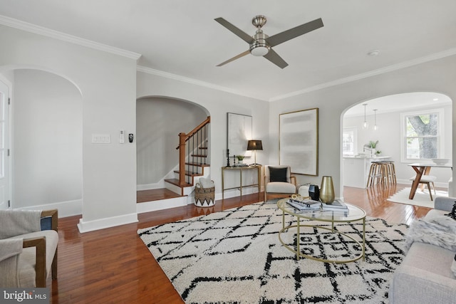 living room with arched walkways, ceiling fan, wood finished floors, and ornamental molding