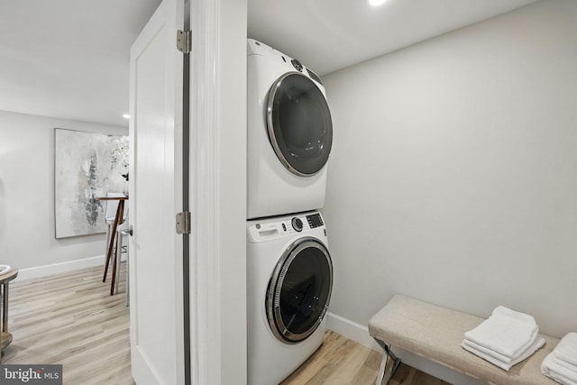washroom with laundry area, light wood-style floors, baseboards, and stacked washer / dryer