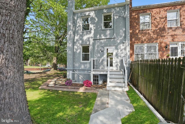 view of front of property with fence, a chimney, a front lawn, and brick siding