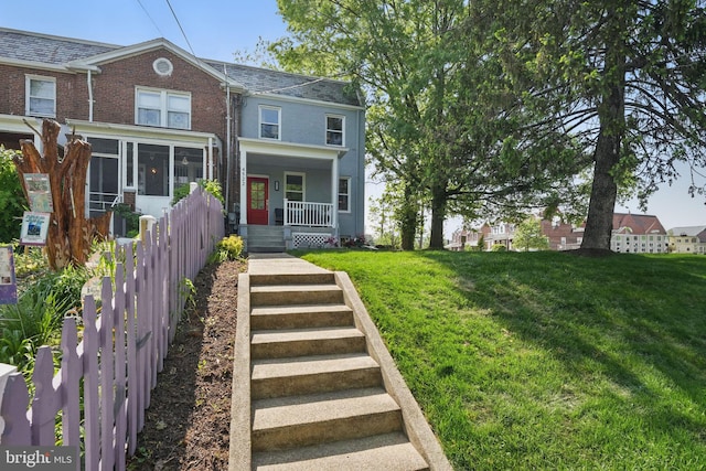 view of front facade featuring a high end roof, a front yard, a porch, and brick siding