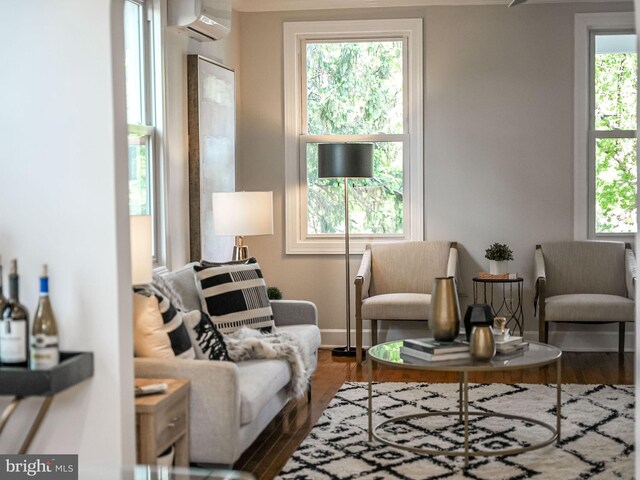 sitting room featuring baseboards, a wealth of natural light, wood finished floors, and a wall mounted air conditioner