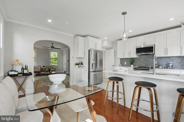 kitchen with light countertops, stainless steel appliances, arched walkways, and a breakfast bar