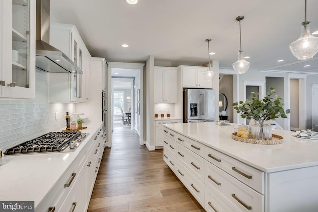 3919 Pineland St, Fairfax, VA 22031 - kitchen featuring appliances with stainless steel finishes, wall chimney exhaust hood, white cabinetry, wood finished floors, and backsplash