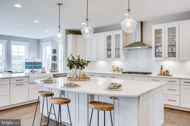 3919 Pineland St, Fairfax, VA 22031 - kitchen with gas cooktop, a kitchen island, a sink, light countertops, and wall chimney exhaust hood