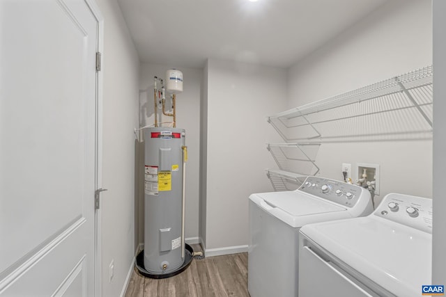 clothes washing area featuring laundry area, electric water heater, baseboards, light wood-type flooring, and washing machine and clothes dryer