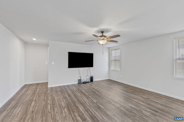 unfurnished living room featuring baseboards, a ceiling fan, and wood finished floors