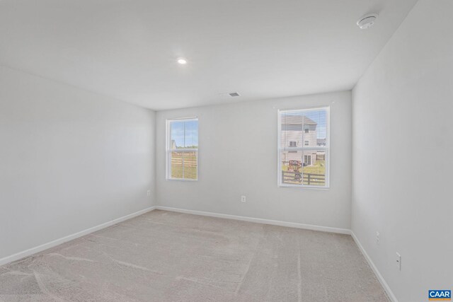 empty room with baseboards, light carpet, recessed lighting, and visible vents