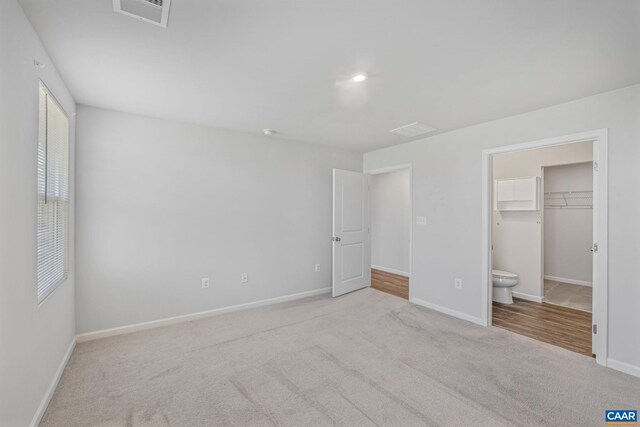 unfurnished bedroom featuring visible vents, baseboards, carpet floors, and a spacious closet