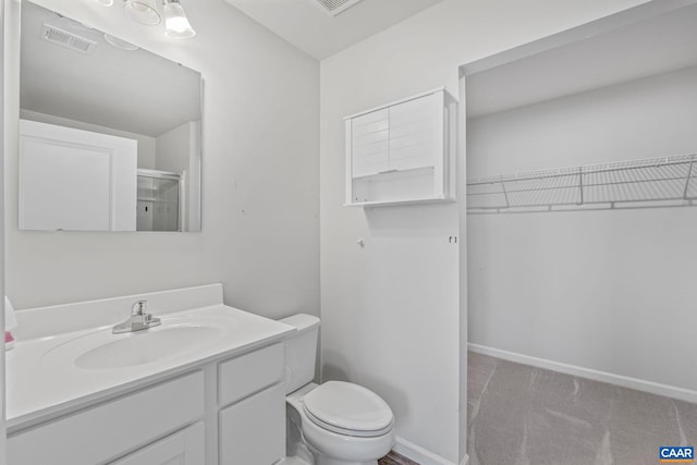 full bath featuring visible vents, vanity, toilet, a walk in closet, and a shower stall