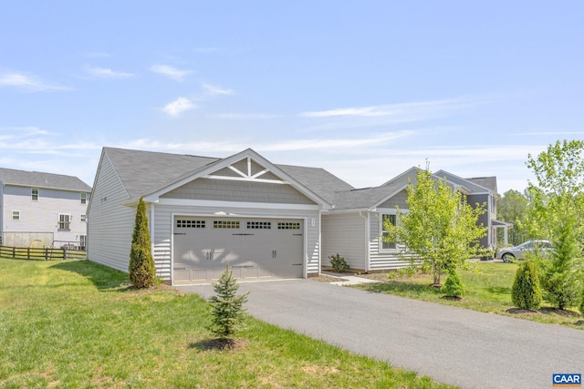 craftsman house with fence, an attached garage, driveway, and a front lawn