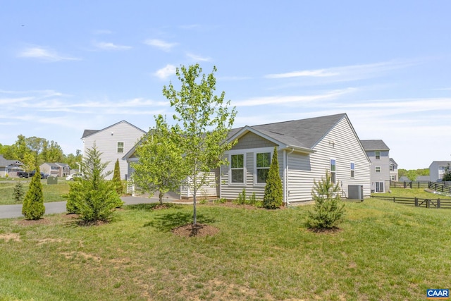 exterior space with central AC unit, fence, and a yard