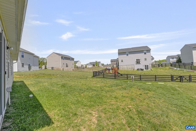 view of yard featuring a playground, fence, and a residential view