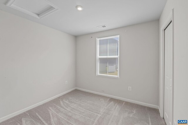 unfurnished bedroom with baseboards, visible vents, light carpet, and attic access