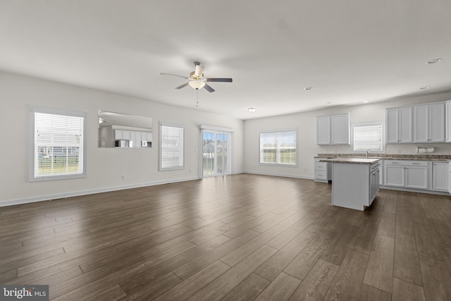unfurnished living room with dark wood-type flooring, a ceiling fan, baseboards, and recessed lighting