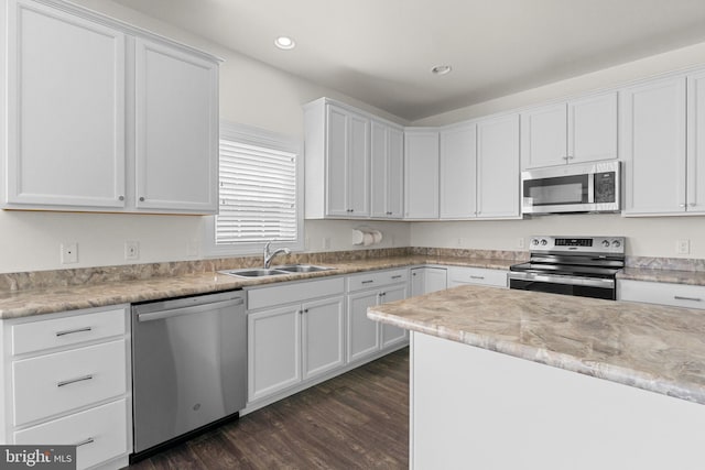kitchen featuring dark wood-style flooring, recessed lighting, white cabinets, a sink, and appliances with stainless steel finishes