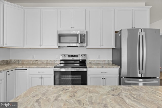 kitchen featuring appliances with stainless steel finishes, white cabinets, and light stone countertops