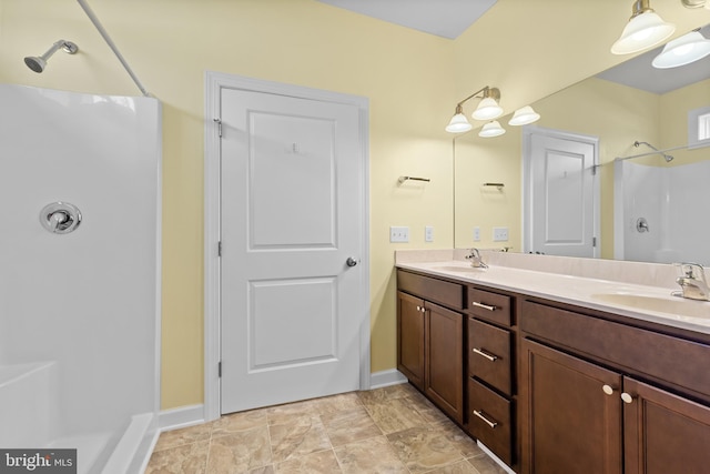 full bathroom featuring baseboards, walk in shower, and a sink
