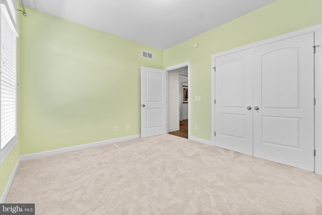 unfurnished bedroom featuring visible vents, baseboards, carpet floors, and a closet