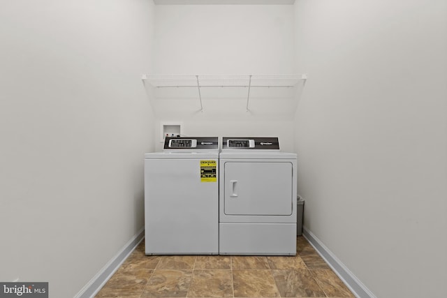 laundry room featuring baseboards, laundry area, stone finish flooring, and washing machine and clothes dryer