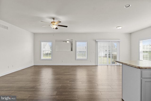 unfurnished living room with visible vents, a ceiling fan, baseboards, and dark wood-style floors